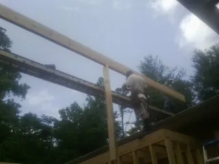 Carpenter setting a ridge beam over a new addition frame — Ice Dam Removal by Roofing Brothers in Nakina