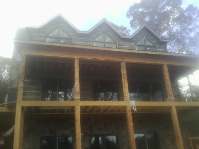 Dormers and porch framing on a large log home under construction — Roof Coating work by our crew in Nakina