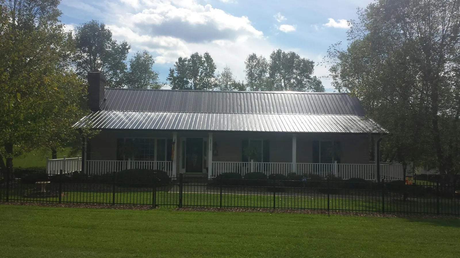 Gray metal roof on a brick ranch with a full width front porch — Gutter Guard Installation work by our crew in Nakina