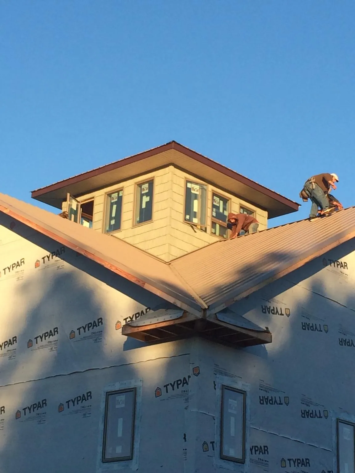 Roofers working around a rooftop cupola on a new metal roof at sunset — Roof Waterproofing in Nakina by Roofing Brothers
